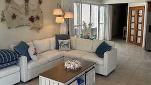 Una sala de estar moderna con un sofá modular, una mesa de centro de madera y un ventilador de techo.