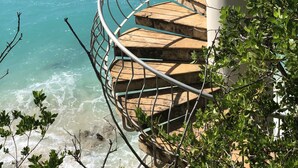 Una escalera de caracol que lleva a un balcón con vistas al mar turquesa.