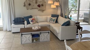 Una sala moderna con un sofá modular, una mesa de centro de madera y una mesa de comedor con sillas.