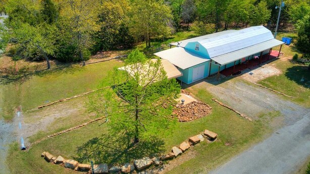 A single-story building with a flat roof and a large garage. It is surrounded by a well-maintained lawn and a wooded area.