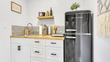 A modern kitchen with a black refrigerator, white cabinets, and a wooden countertop.