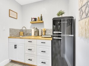 Eine moderne Küche mit einem schwarzen Kühlschrank, weißen Schränken und einer Holzausziehtafel.