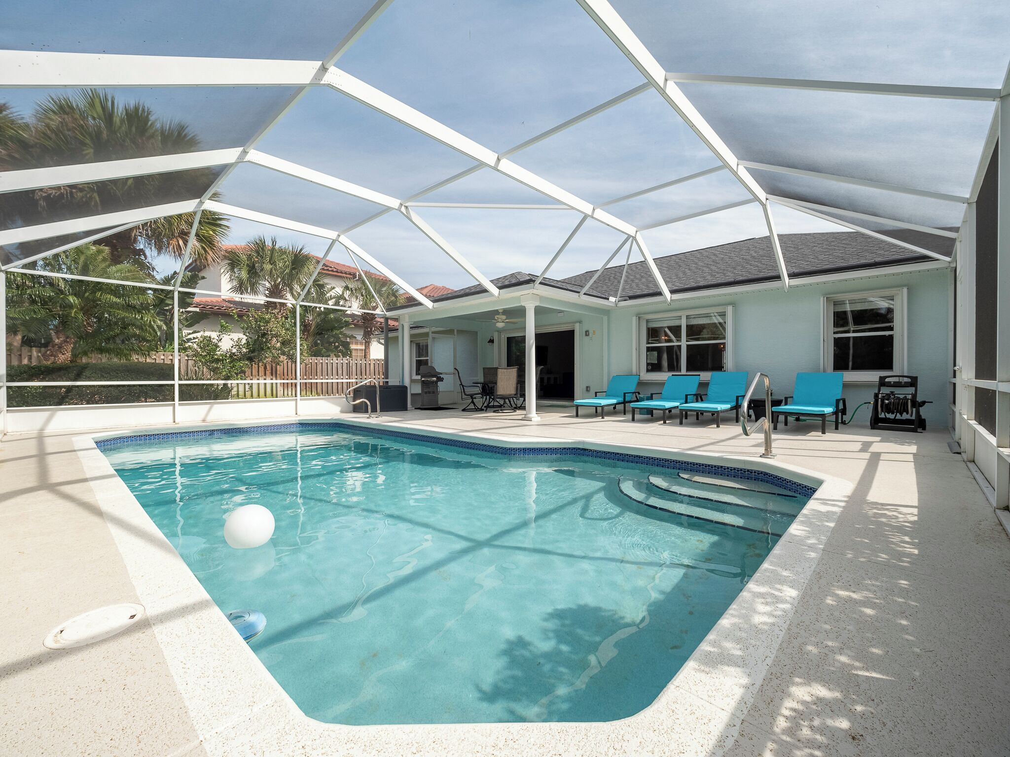 Una piscina coperta con un elemento d'acqua cristallina e azzurra, circondata da sedie a sdraio e una terrazza.