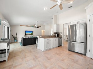 A spacious kitchen with a central island, stainless steel appliances, and a ceiling fan. - Complete Searenity by Distinctive Beach Rentals (Palm Coast)
