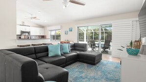 A modern living room with a sectional sofa, a round coffee table, and a ceiling fan. - Complete Searenity by Distinctive Beach Rentals (Palm Coast)
