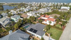 An aerial view of a residential area with houses, a body of water, and a beach in the background. - Complete Searenity by Distinctive Beach Rentals (Palm Coast)