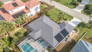 An aerial view of a house with a swimming pool, solar panels, and a well-maintained lawn. - Complete Searenity by Distinctive Beach Rentals (Palm Coast)