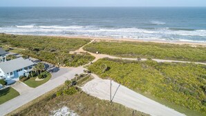 A coastal property with a beach view, a paved driveway, and a building with a blue roof. - Complete Searenity by Distinctive Beach Rentals (Palm Coast)