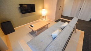 A modern hotel room with a sofa, a bedside table, a lamp, and a flat-screen TV mounted on the wall. - Rinn Horikawa Gojo (Kyoto)