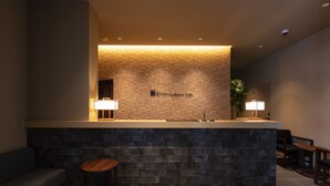A reception area with a stone counter, a sofa, and a small round table. - Rinn Horikawa Gojo (Kyoto)