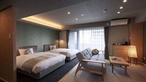A modern hotel room with two beds, a sofa, a small table, and a desk. - Rinn Horikawa Gojo (Kyoto)