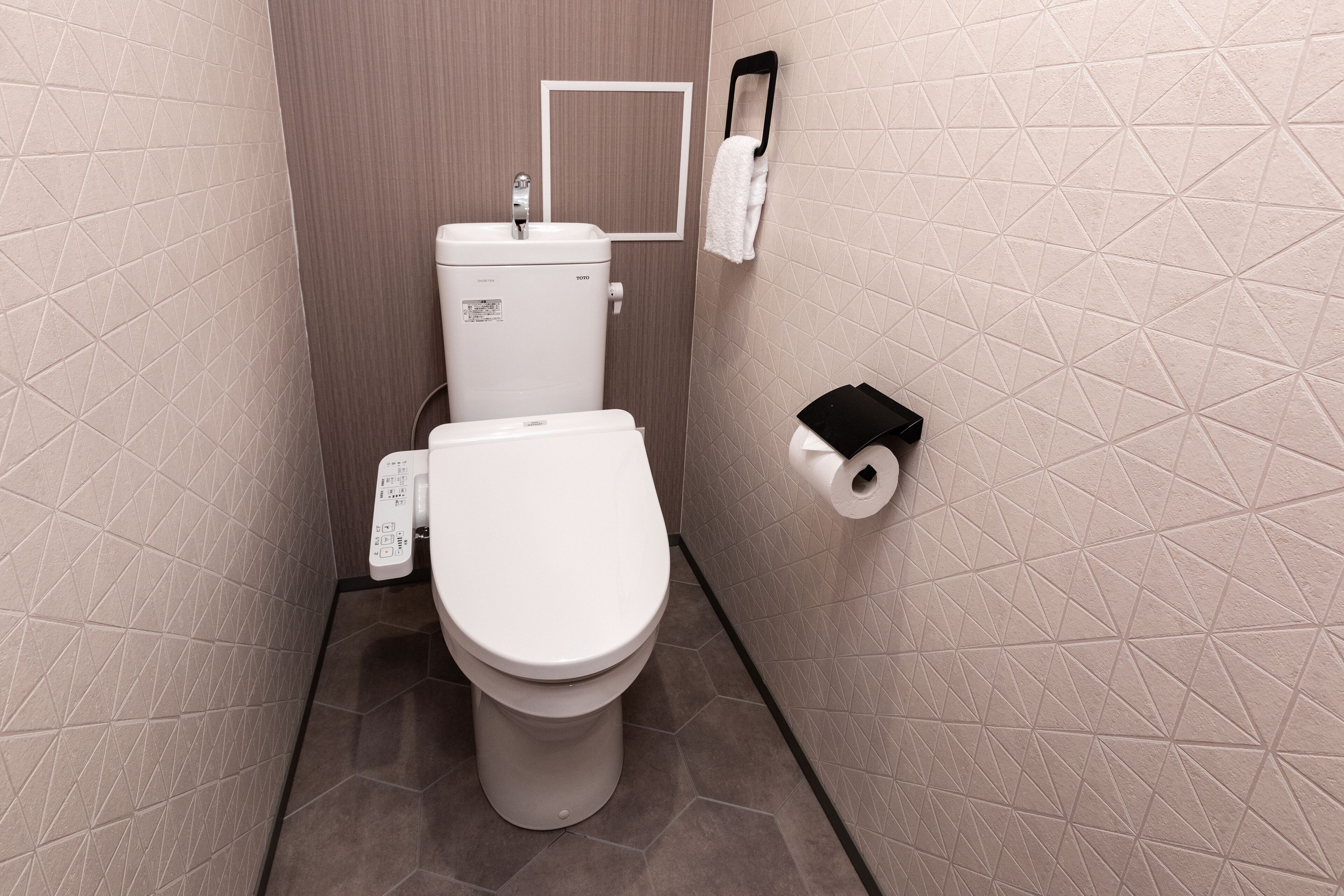 A small, modern bathroom with a toilet, a sink, and a towel rack.