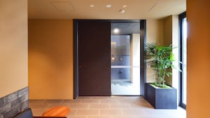 A modern lobby with a seating area, a glass door leading to a hallway, and a potted plant. - Rinn Horikawa Gojo (Kyoto)