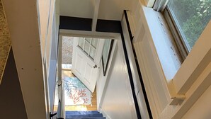 A staircase with white walls and a window on the right.