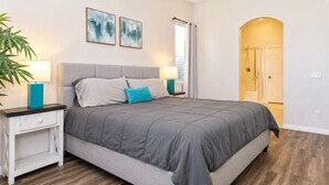 A bedroom with a bed, nightstands, a lamp, a potted plant, and abstract art on the wall. - Home Theater, Arcade games, Water Slide, Lagoon-Style Pool & Extra-Large Spa (Indio)