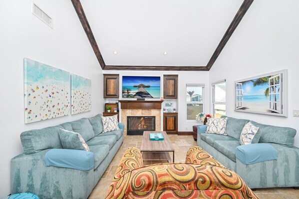 A living room with two sofas, a fireplace, and artwork on the walls.