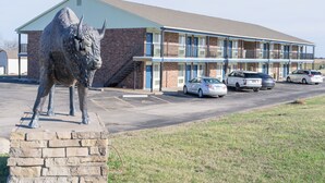 A motel with a bull statue in front, a brick building, and several cars parked in the driveway. - Lebo Inn (Waverly)
