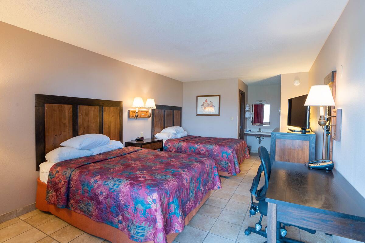 Habitación de hotel con dos camas, un escritorio y una silla.