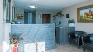A reception area with a blue reception desk, a wooden door, a clock, and a painting of horses on the wall. - Lebo Inn (Waverly)