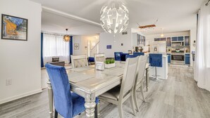 Un'area pranzo moderna con un tavolo in vetro, sedie rivestite in blu e un originale lampadario sferico.