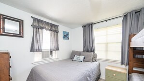 A bedroom with a bed, a nightstand, a dresser, and a window with curtains. - "Peace At Bay" - Home on Caney Creek, Just Minutes to ICW, Gulf & Sargent Beach (Bay City)