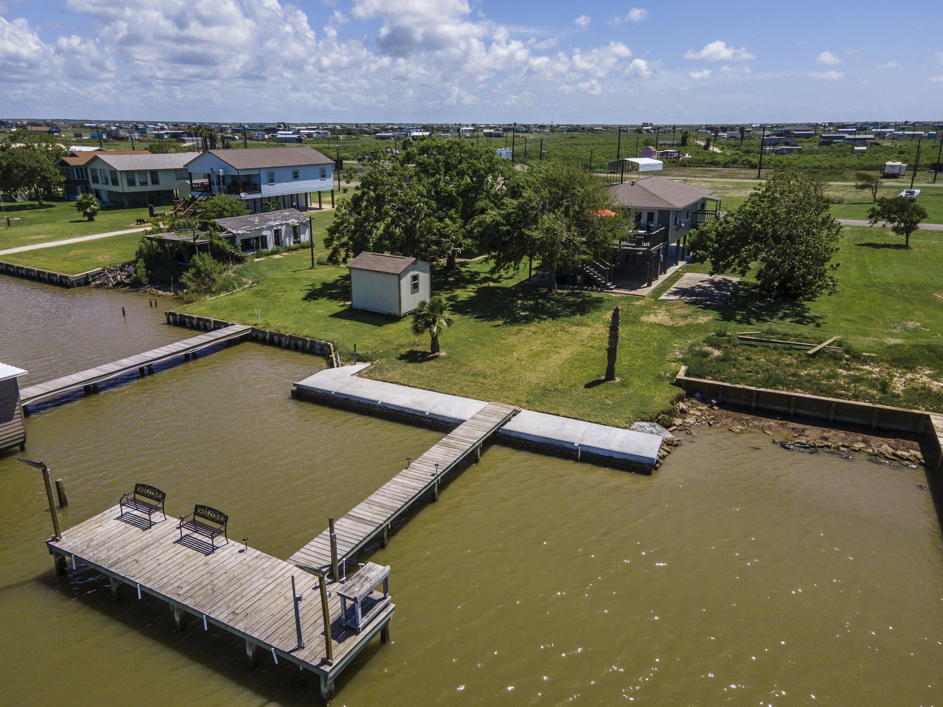 A waterfront property with a dock, a small shed, and a house with a porch.