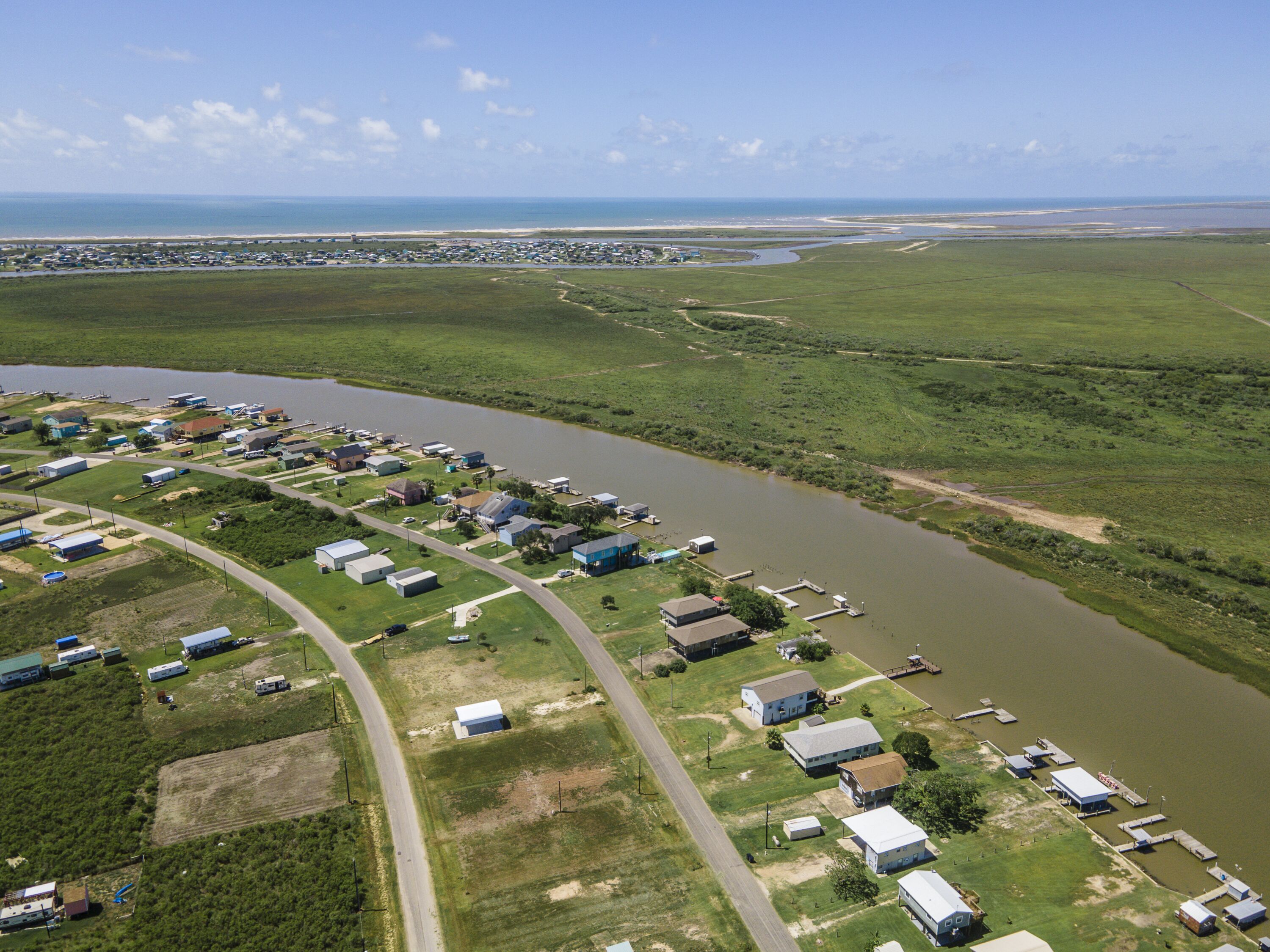 An aerial view of a riverside community with houses and docks along the water.