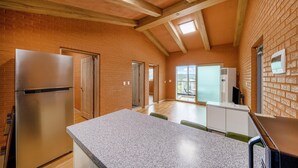 Una cocina con encimera de granito, refrigerador de acero inoxidable y puerta corrediza de vidrio que da a un balcón.
