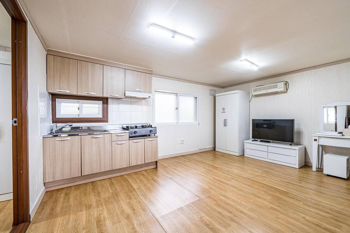 A modern kitchen with wooden cabinets, a built-in stove, and a large window.