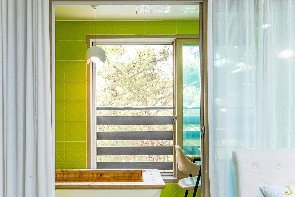 A room with a window, a chair, and a desk with a lamp.