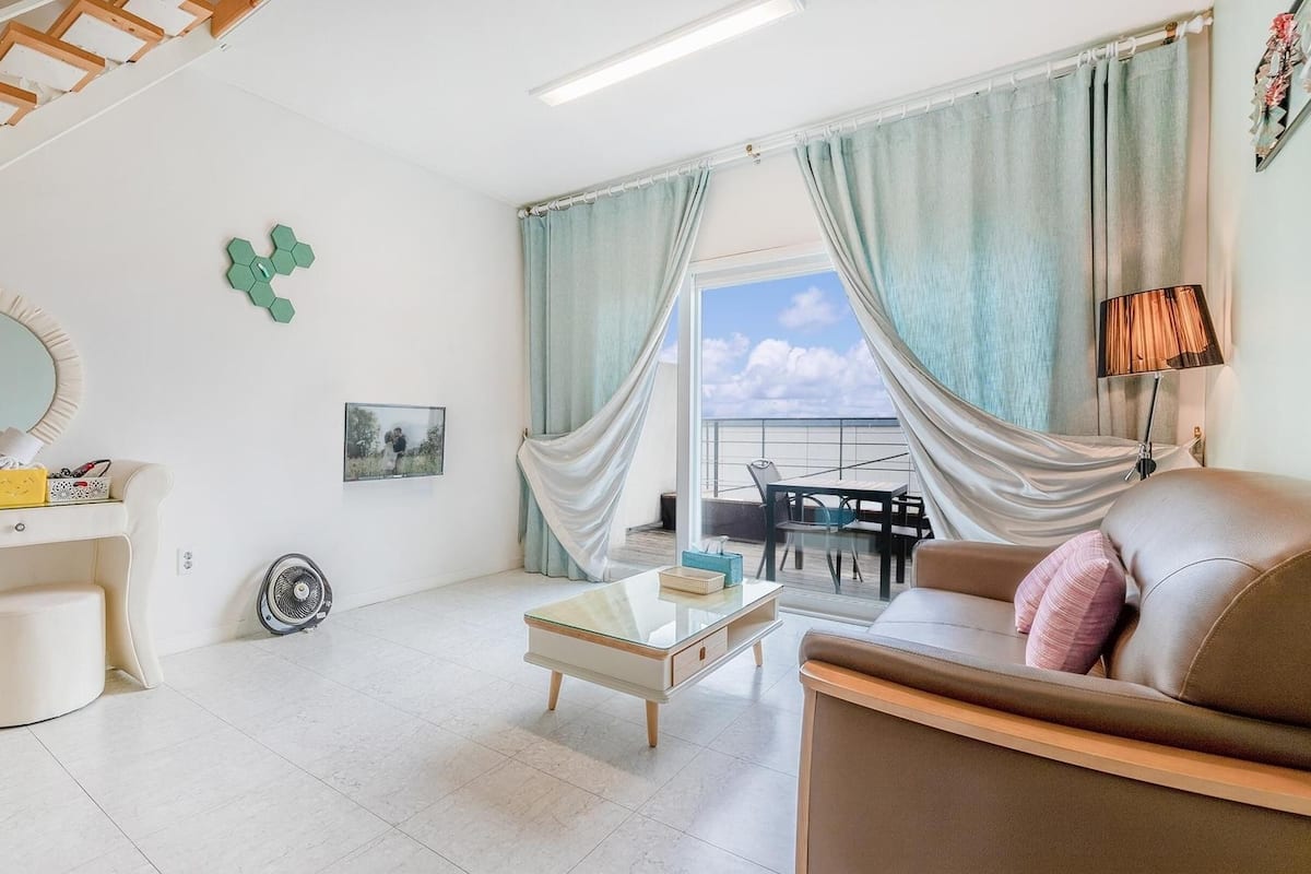Ein modernes Wohnzimmer mit Treppe, Essbereich mit Blick und einem Balkon.