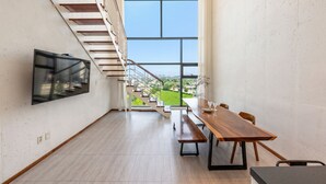 Ein modernes Interieur mit Treppe, Essbereich und großem Fenster mit Blick auf die Stadt.