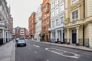 Une rue bordée d’immeubles à plusieurs étages, dont une rangée de maisons de ville et un bâtiment moderne à la façade en verre.