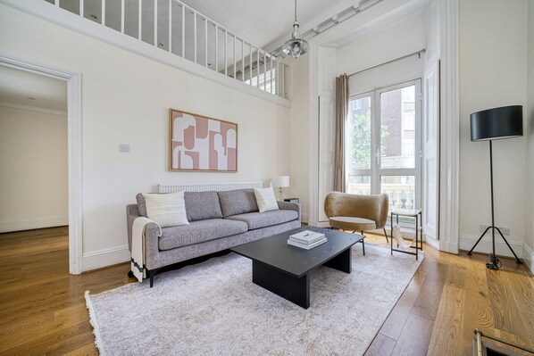 Un salon spacieux avec un canapé gris, une table basse noire et un fauteuil beige.