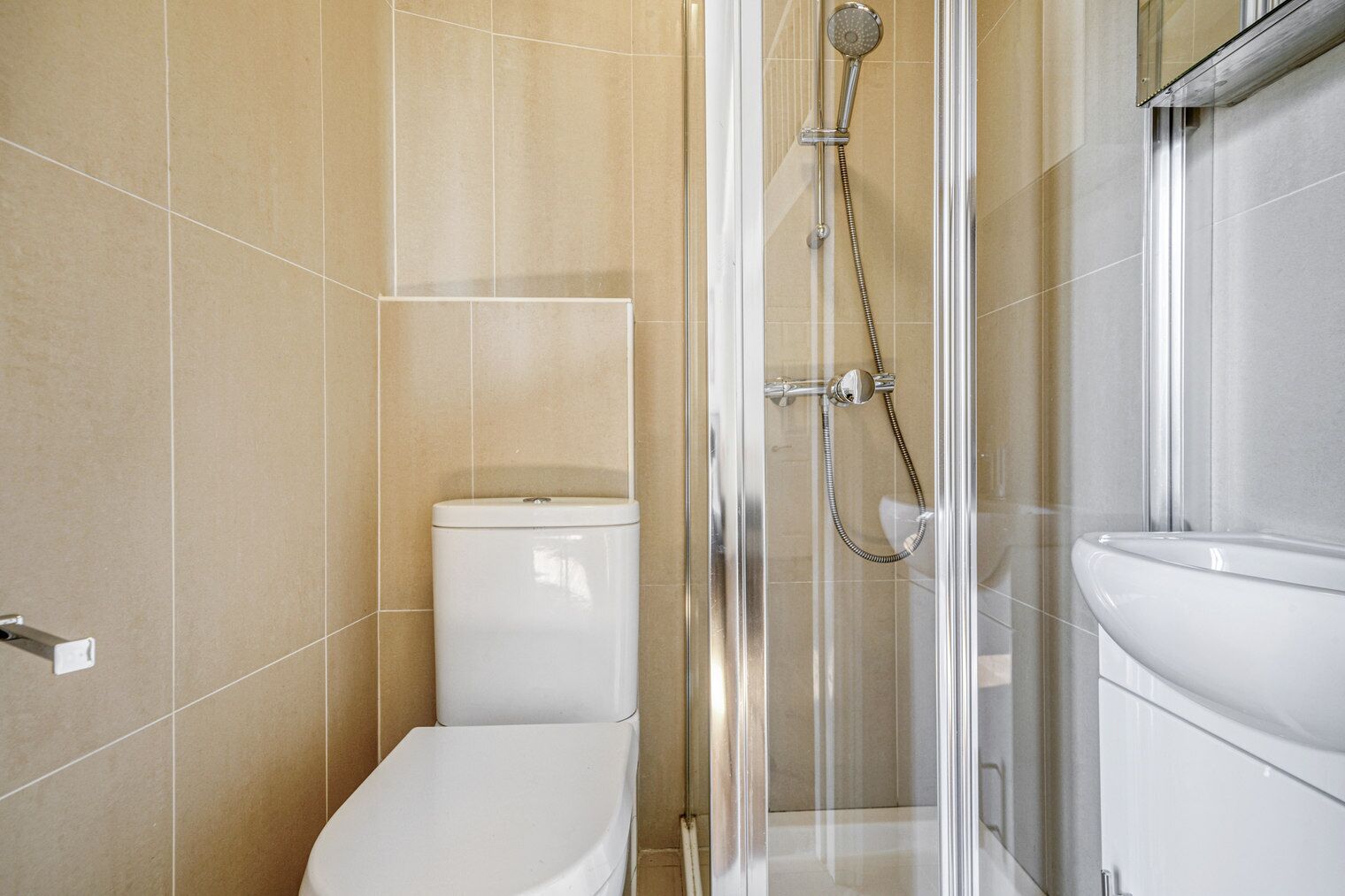 A modern bathroom with a glass-enclosed shower, a toilet, and a sink.