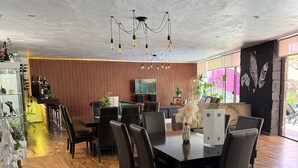 Un amplio comedor con una mesa y sillas de madera, un televisor y un adorno en la pared.