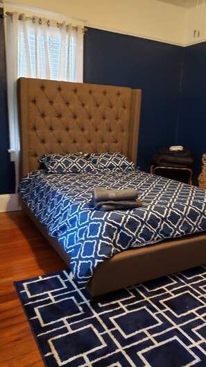 A bedroom with a tufted headboard, a patterned bedspread, and a matching rug.