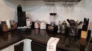 Ett kök med en kaffebryggare, en mixer och diverse köksredskap.