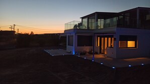 A modern two-story house with a glass balcony, a covered patio, and a driveway with blue lights. - BlueTel Lixouri, Greece (Lixouri)