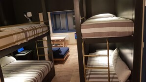 A dorm-style room with bunk beds, a desk with a laptop, a chair, and a window with blinds. - BlueTel Lixouri, Greece (Lixouri)