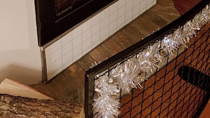 A fireplace with a wooden mantel, a small Christmas tree, and a 'relax' sign.