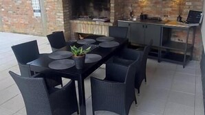 An outdoor patio with a brick fireplace, a dining table with chairs, and a bar area.