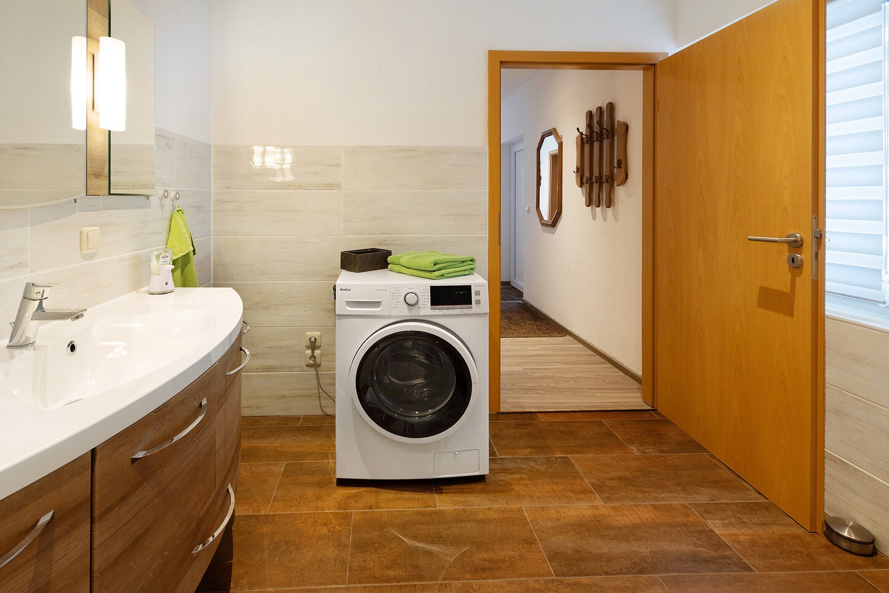 Ein modernes Badezimmer mit integrierter Waschmaschine, einem großen Waschbecken und einer Holztür.