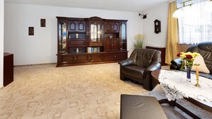 A living room with a large wooden cabinet, leather sofa, and a table with a lace tablecloth.