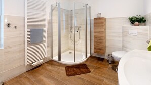 A modern bathroom with a glass-enclosed shower, a white sink, and a wooden cabinet.