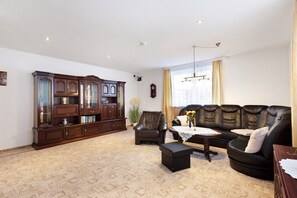 A living room with a dark wooden cabinet, leather sofa, and a small table with a vase. - Family-Friendly Apartment "Fuchsbaude" with Wi-Fi (Allrode)
