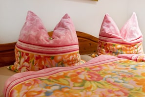 Ein Bett mit blumigem Bettzeug und rosafarbenen Kissen.