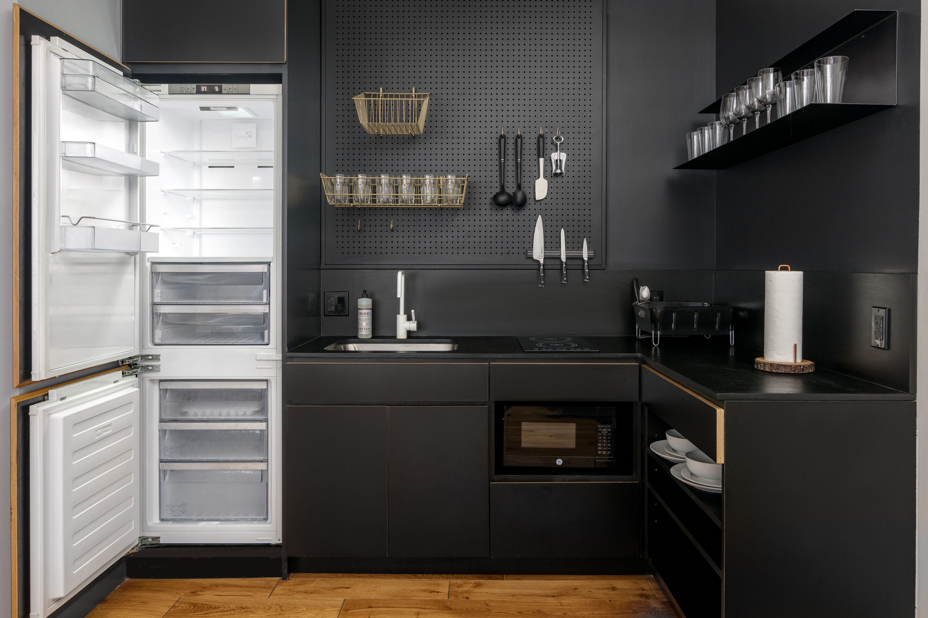 Une cuisine moderne équipée d’un réfrigérateur encastré, d’un évier et d’un four à micro-ondes.