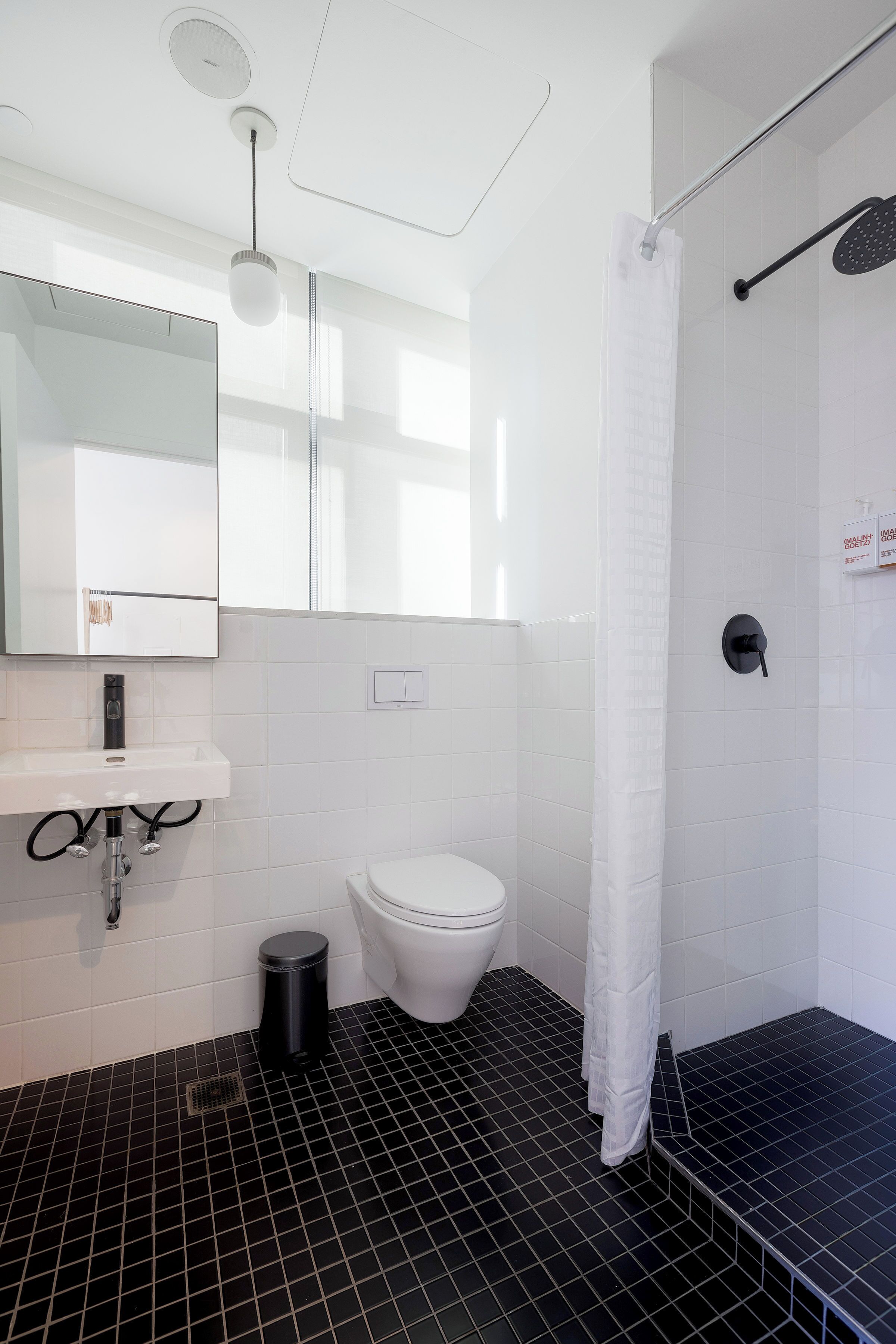 A modern bathroom with a white sink, toilet, and shower area.
