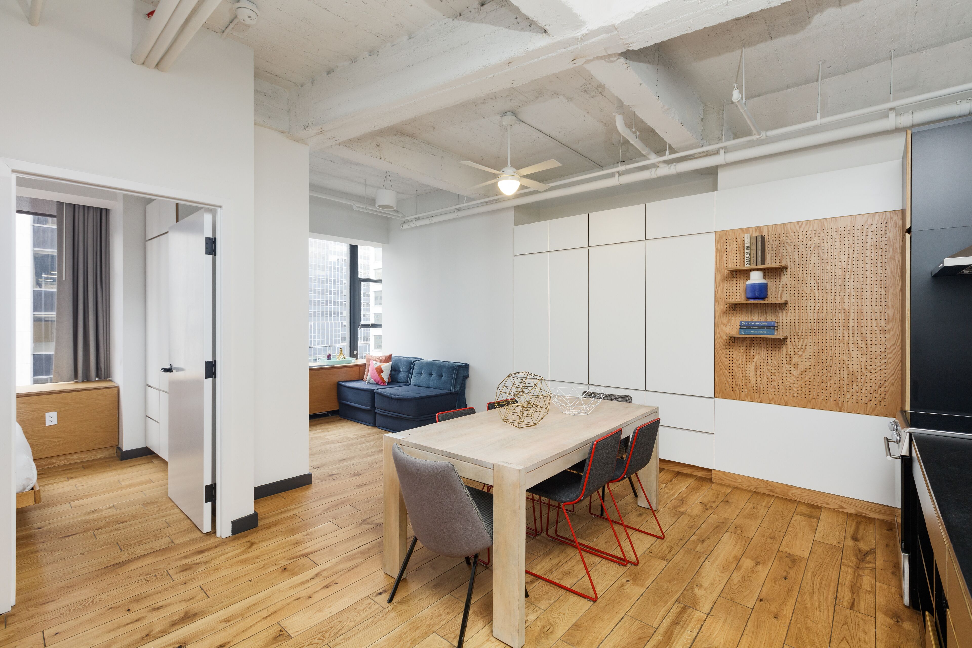 Un interior moderno con una mesa de comedor de madera, sillas y un ventilador de techo.